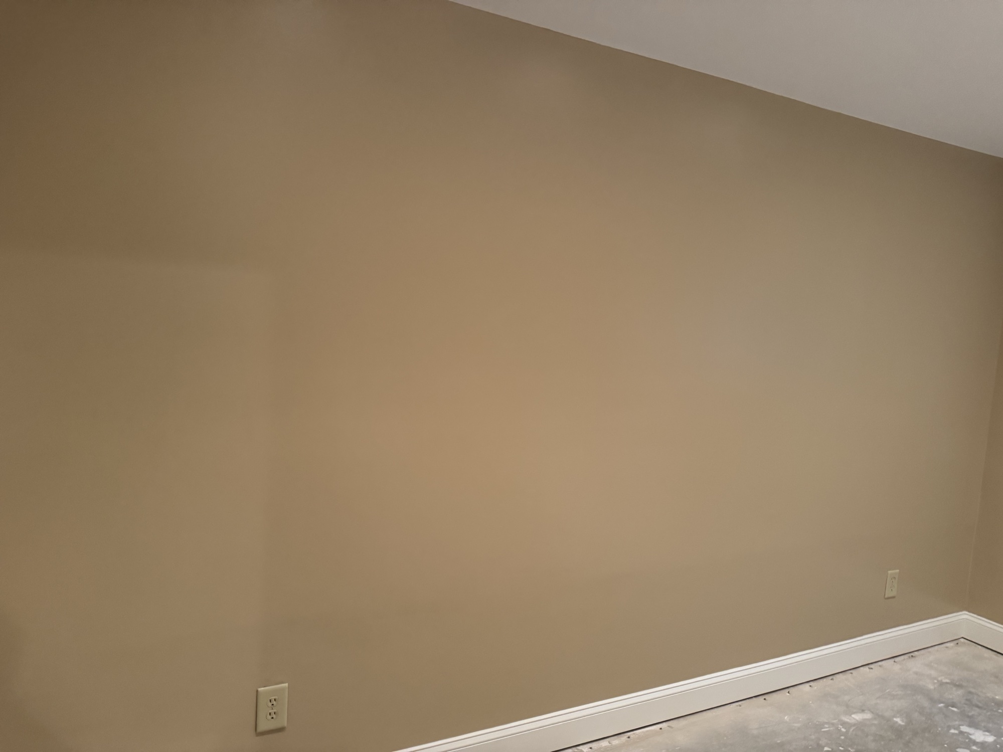 Smooth finished wall with freshly painted baseboard